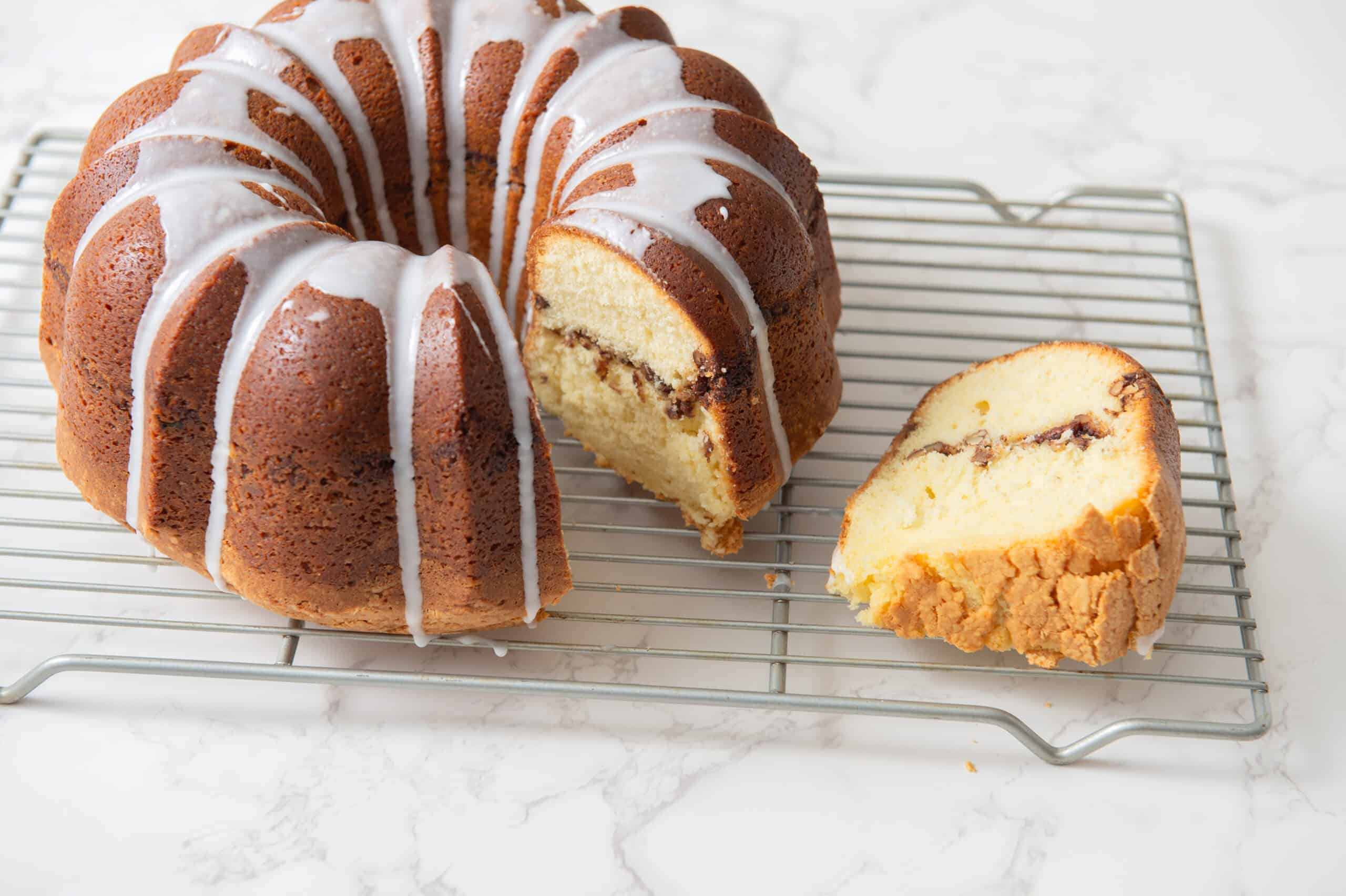 Butter cake with chocolate filling and white icing glaze, sliced to show moist interior with chocolate swirls, on cooling rack, delicious homemade dessert, perfect for celebrations and tea time.