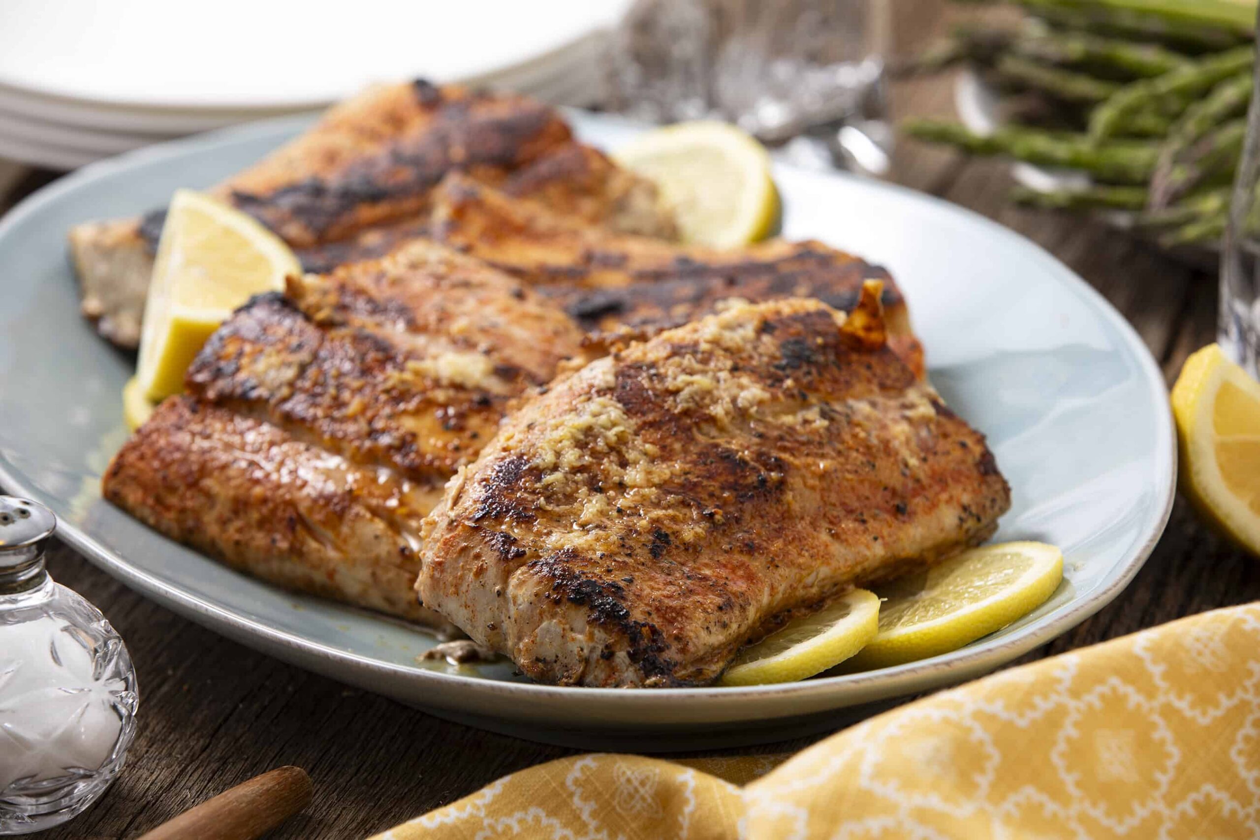 Juicy, seasoned baked salmon fillets with lemon slices on a white serving platter, garnished for a delicious, healthy seafood meal.