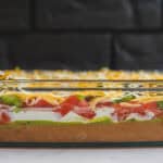 Layers of fresh vegetables, cheese, and creamy sauce in a glass baking dish for delicious casserole or layered dip. Perfect for easy, colorful party recipes and homemade comfort food.