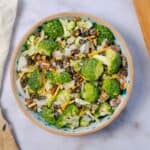 Fresh broccoli and vegetable salad with shredded cheese, black beans, and diced onions in a decorative ceramic bowl.