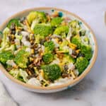 Fresh broccoli salad with cheese, onions, bacon bits, black beans, and shredded cheese served in a decorative bowl for a healthy, tasty meal.