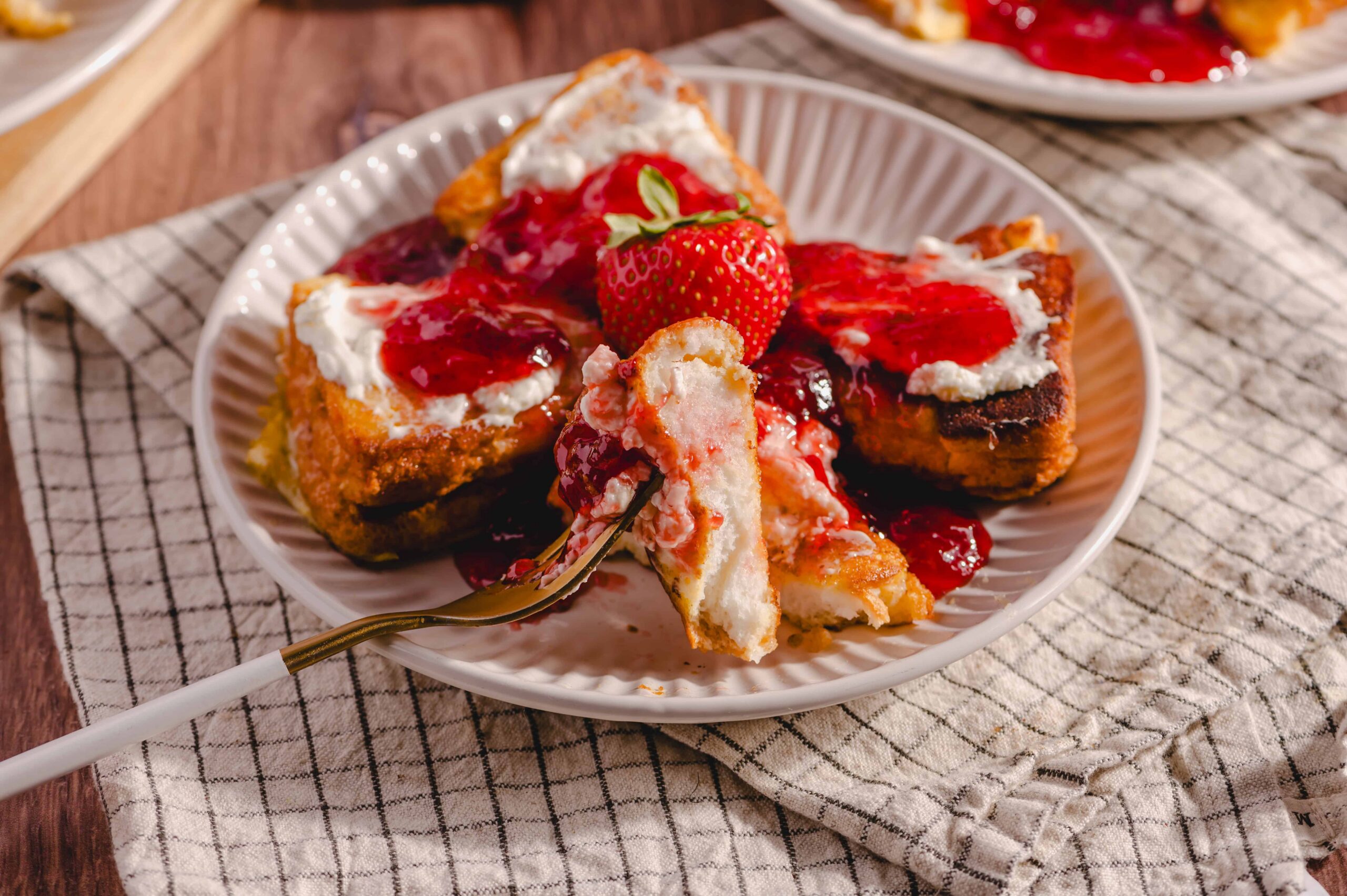 Fresh strawberry shortcake with whipped cream and strawberry topping served on a white plate. Cheesecake with strawberry sauce and fresh fruit garnished with a whole strawberry. Bright and delicious dessert ideal for summer or special occasions.