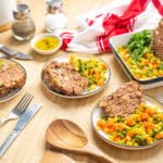 Savory meatloaf served with colorful mixed vegetables, including carrots, peas, and corn on a wooden table, highlighting hearty comfort food, home-cooked meal, and seasonal ingredients.