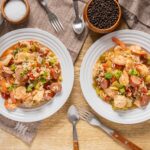 Savory shrimp and sausage fried rice with vegetables served on white plates for a hearty meal.