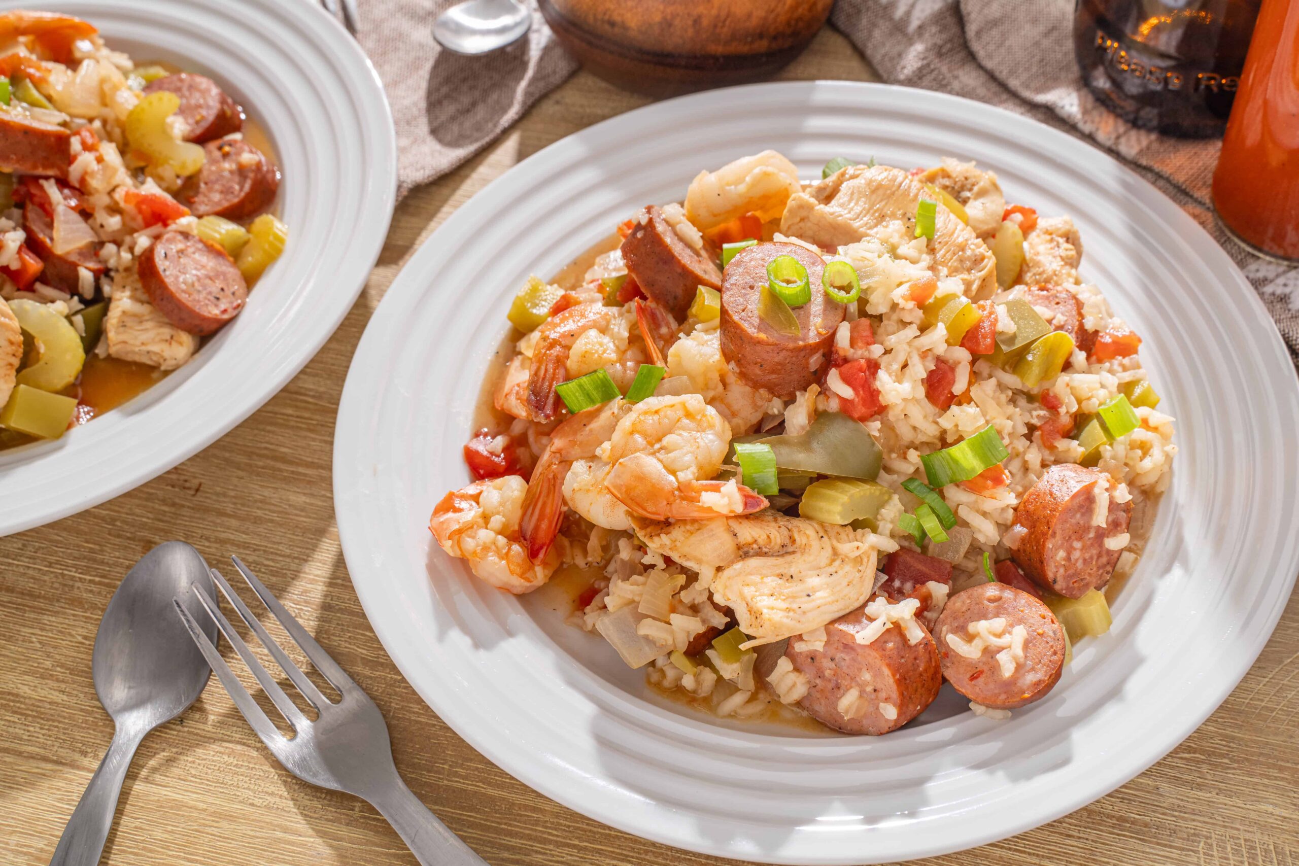 Savory shrimp and sausage jambalaya served with rice, vegetables, and green onions on a white plate. Perfect for a flavorful, hearty seafood and sausage dish.