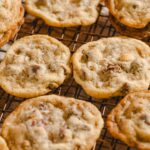 Freshly baked chocolate chip cookies cooling on a wire rack, featuring golden-brown edges and a soft, chewy center filled with melty chocolate chips. Perfect for dessert or snack.