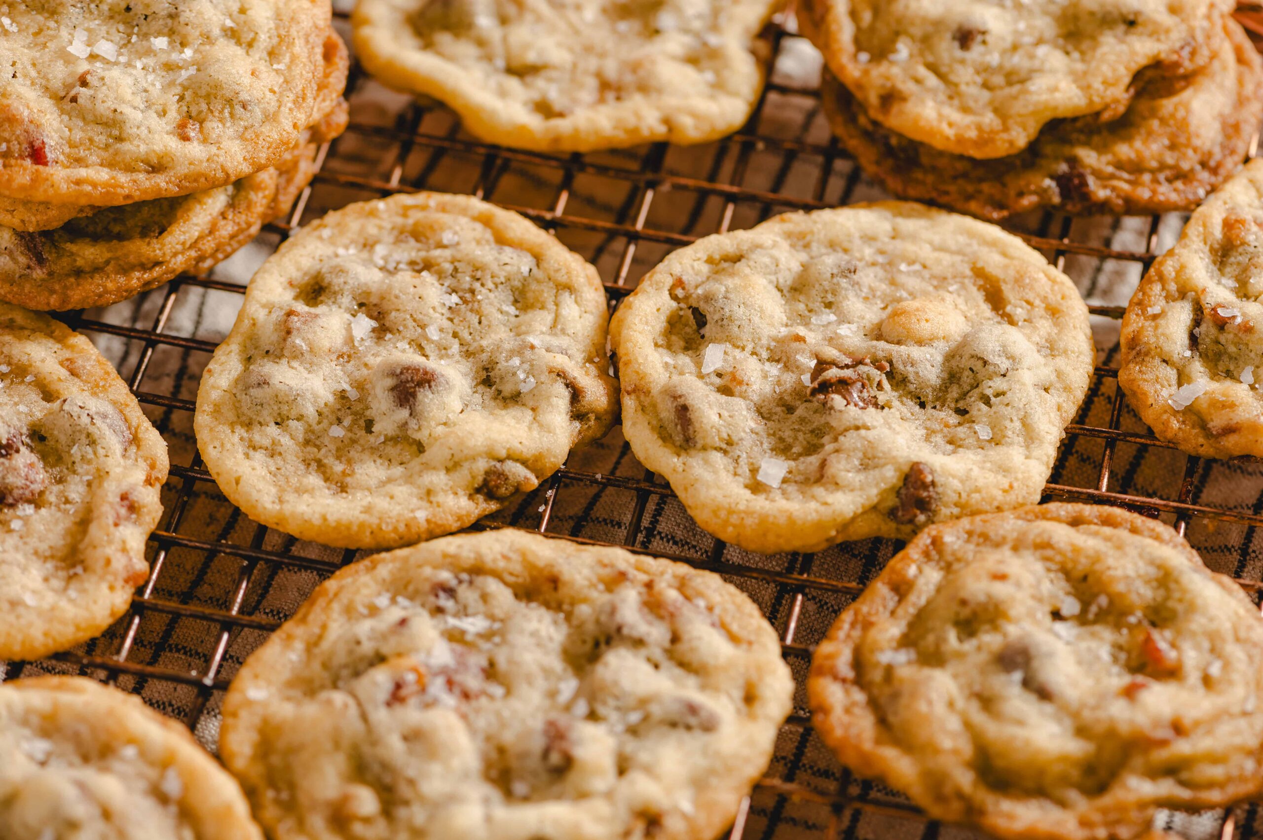 Freshly baked chocolate chip cookies cooling on a wire rack, featuring golden-brown edges and a soft, chewy center filled with melty chocolate chips. Perfect for dessert or snack.