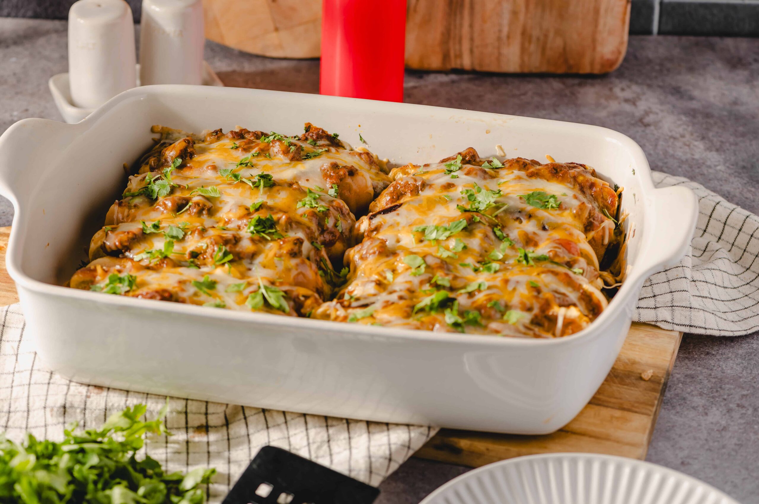 Baked stuffed peppers covered in melted cheese and garnished with fresh cilantro in a white baking dish.