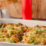 Juicy baked chicken breasts topped with melted cheese and fresh cilantro in a white baking dish, perfect for a flavorful dinner or family meal.