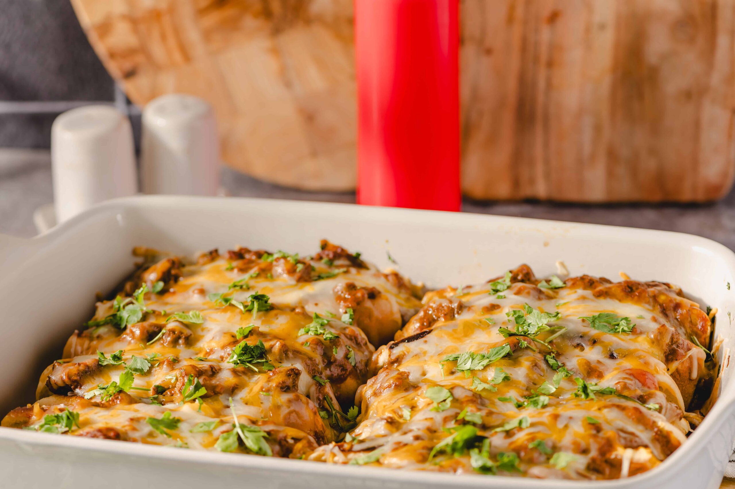 Juicy baked chicken breasts topped with melted cheese and fresh cilantro in a white baking dish, perfect for a flavorful dinner or family meal.
