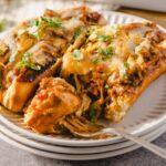Delicious beef and cheese stuffed enchiladas with melted cheese and fresh cilantro on a white plate.
