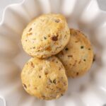Soft and flavorful homemade savory cheese scones with herbs and spices, perfect for breakfast or snacks, served in a white decorative bowl for an inviting presentation.