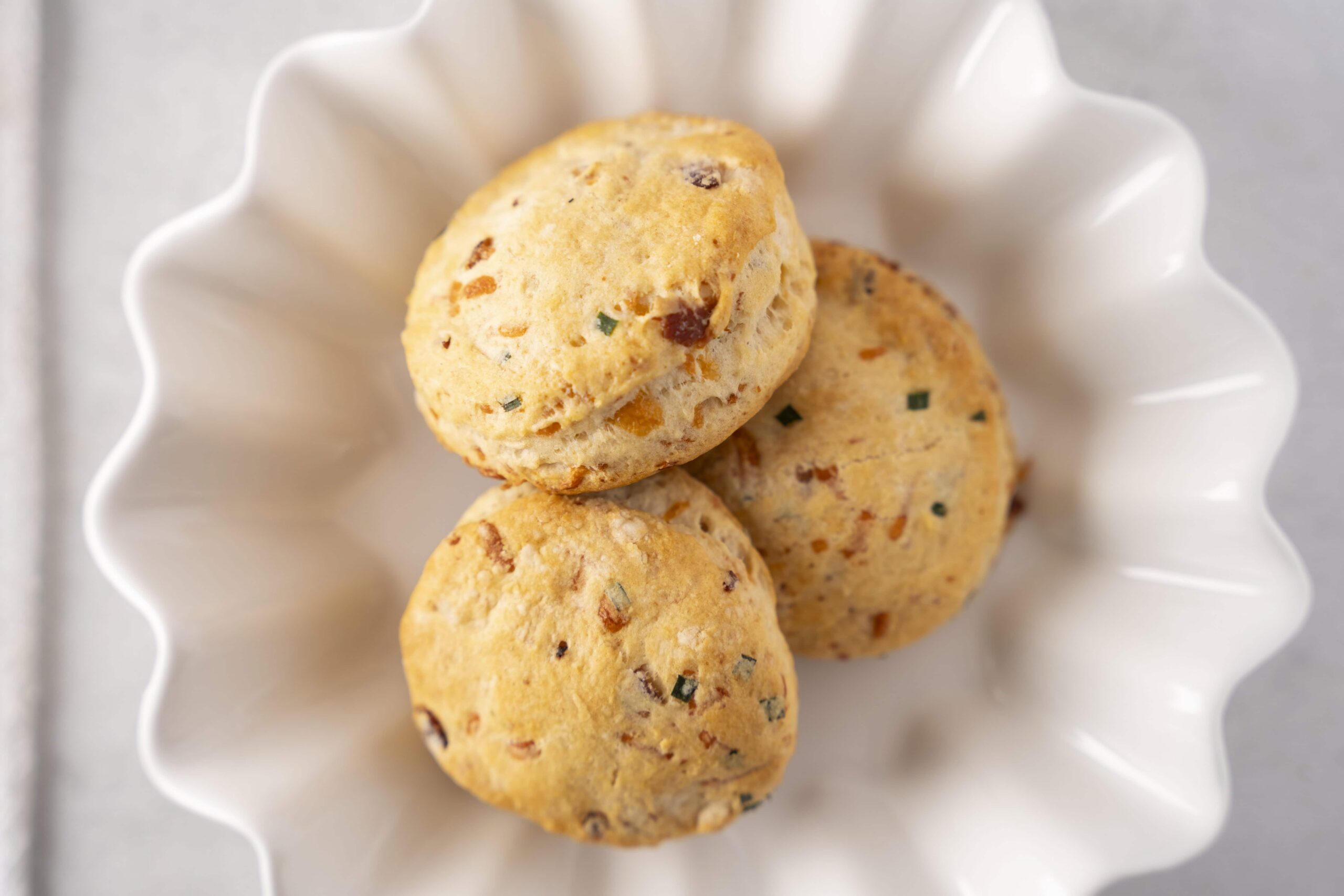 Soft and flavorful homemade savory cheese scones with herbs and spices, perfect for breakfast or snacks, served in a white decorative bowl for an inviting presentation.