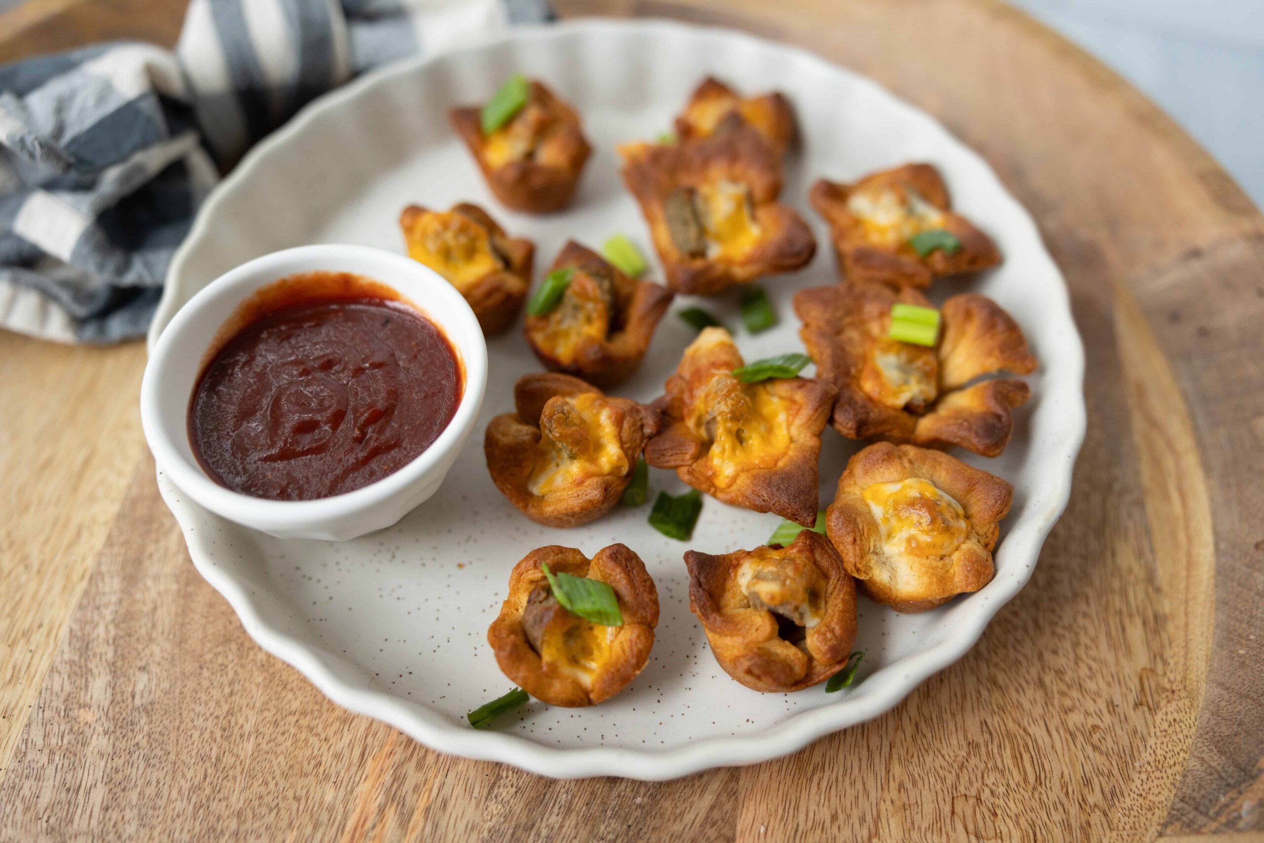 Crispy baked buffalo chicken egg cups garnished with chopped green onions served with a side of spicy buffalo sauce, perfect for a flavorful appetizer or snack.