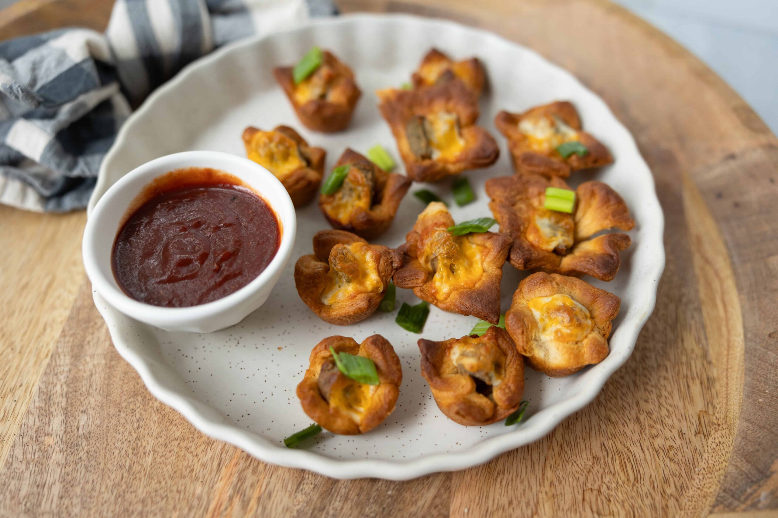 Golden fried jalapeño poppers stuffed with cheese and meat, served with a side of spicy marinara sauce on a rustic white plate. Perfect appetizer for party snacks or casual gatherings.