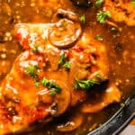 Juicy chicken thighs simmered in a savory herb-infused garlic and mushroom sauce garnished with fresh parsley for a flavorful, comforting meal.