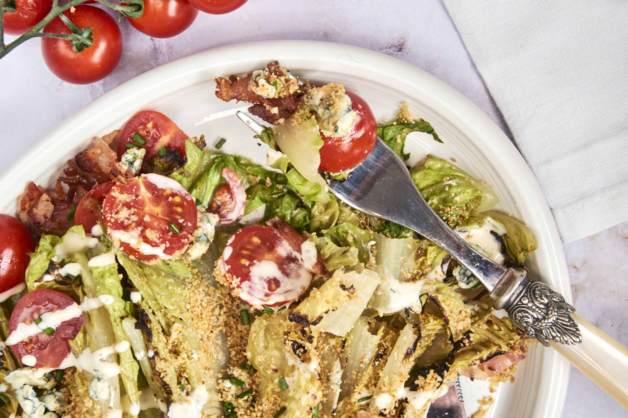 Fresh garden salad with cherry tomatoes, crispy bacon, blue cheese, and creamy dressing, served on a white plate, ideal for healthy eating, summer meals, or easy lunch recipes.