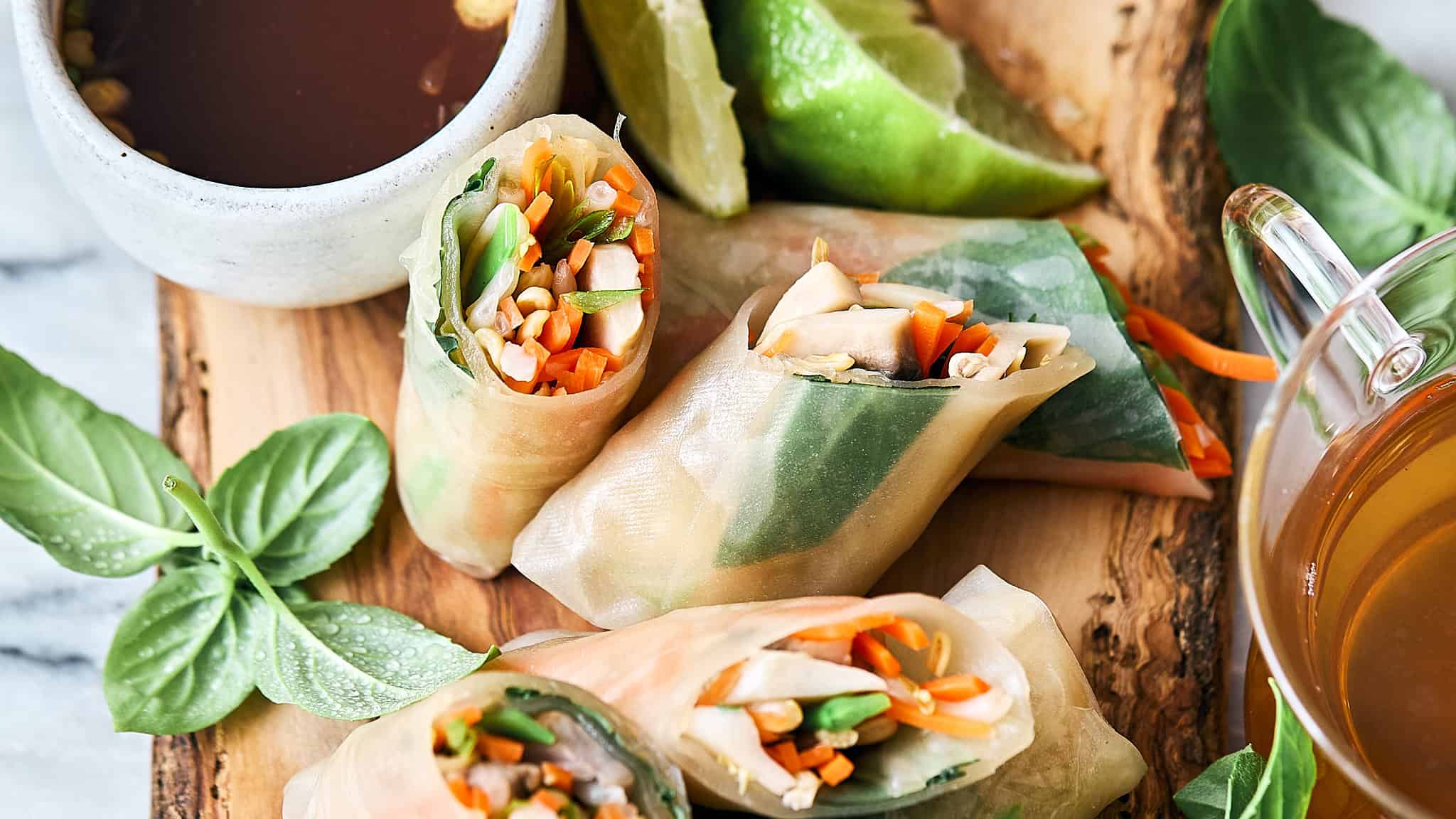 Fresh Vietnamese spring rolls filled with shredded vegetables and herbs, served with dipping sauces on a rustic wooden board. Perfect for healthy, light appetizers or snacks.