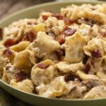 Creamy chicken and bacon pasta dish served in a green bowl, topped with crispy bacon bits, featuring tender chicken chunks and a rich sauce, perfect for comfort food recipes.