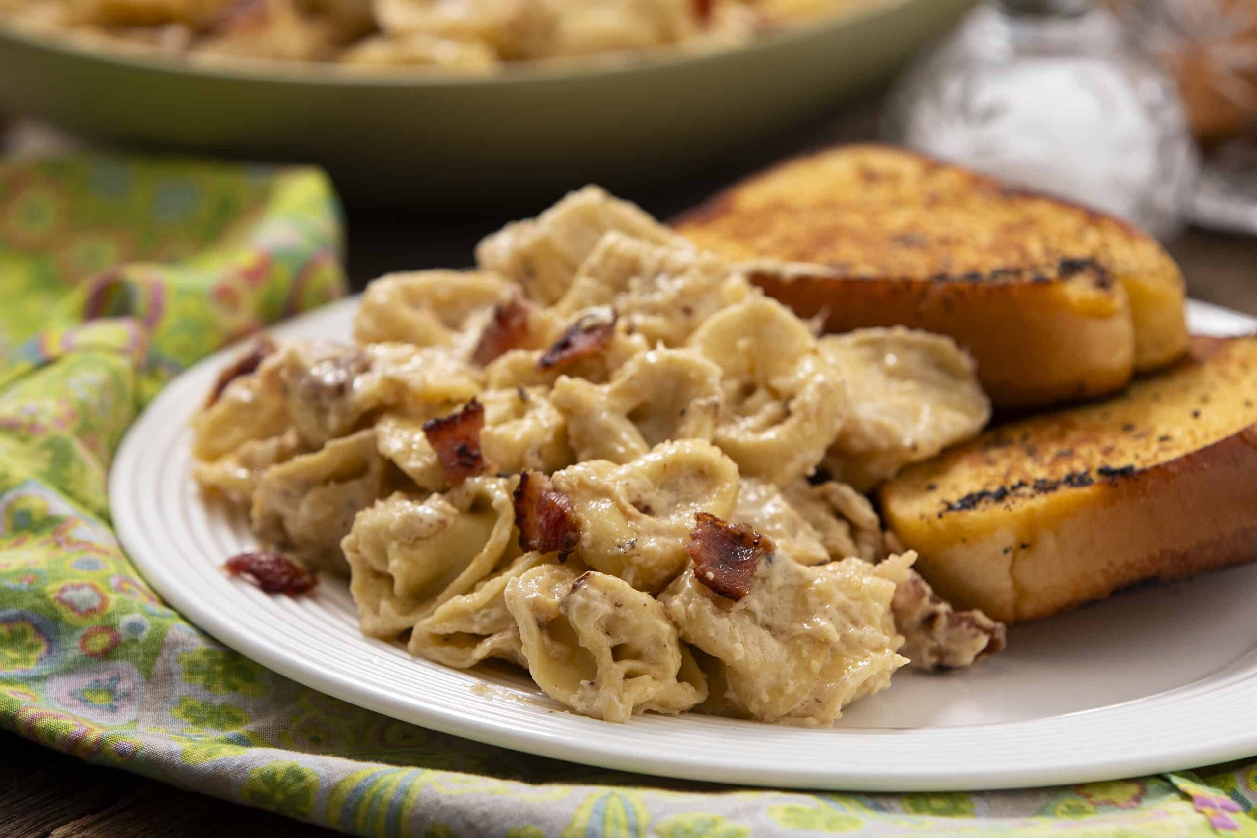 Creamy chicken and bacon pasta served with toasted bread on a white plate. Delicious comfort food featuring tender pasta with bacon bits and rich creamy sauce, perfect for a hearty meal.