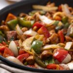 Sautéed vegetable and chicken stir-fry in a black skillet, featuring colorful bell peppers, onions, and tender chicken pieces, perfect for healthy dinner recipes.