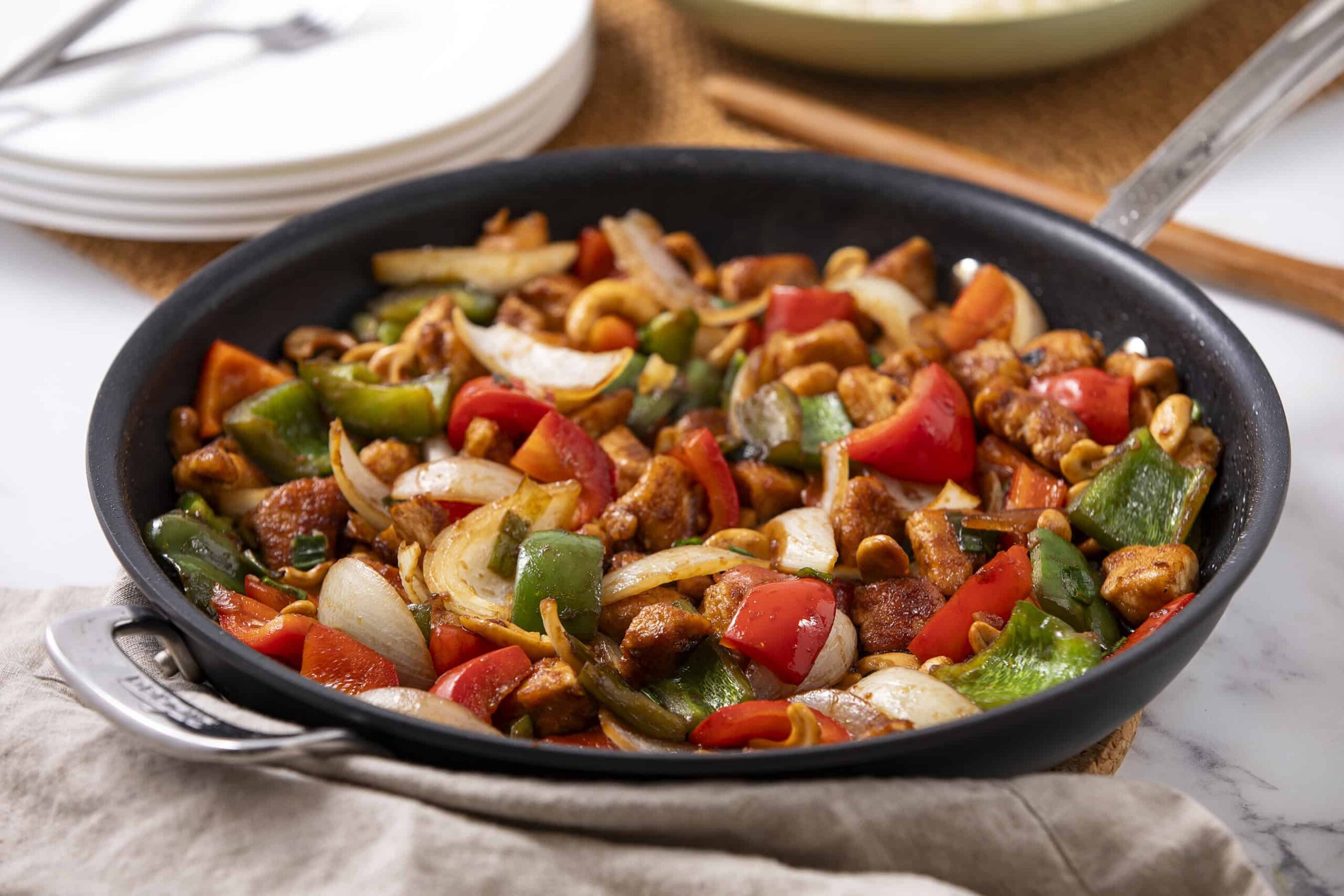 Stir-fried chicken with colorful bell peppers and onions in a black skillet, showcasing a vibrant, healthy, and flavorful Asian-inspired dish.