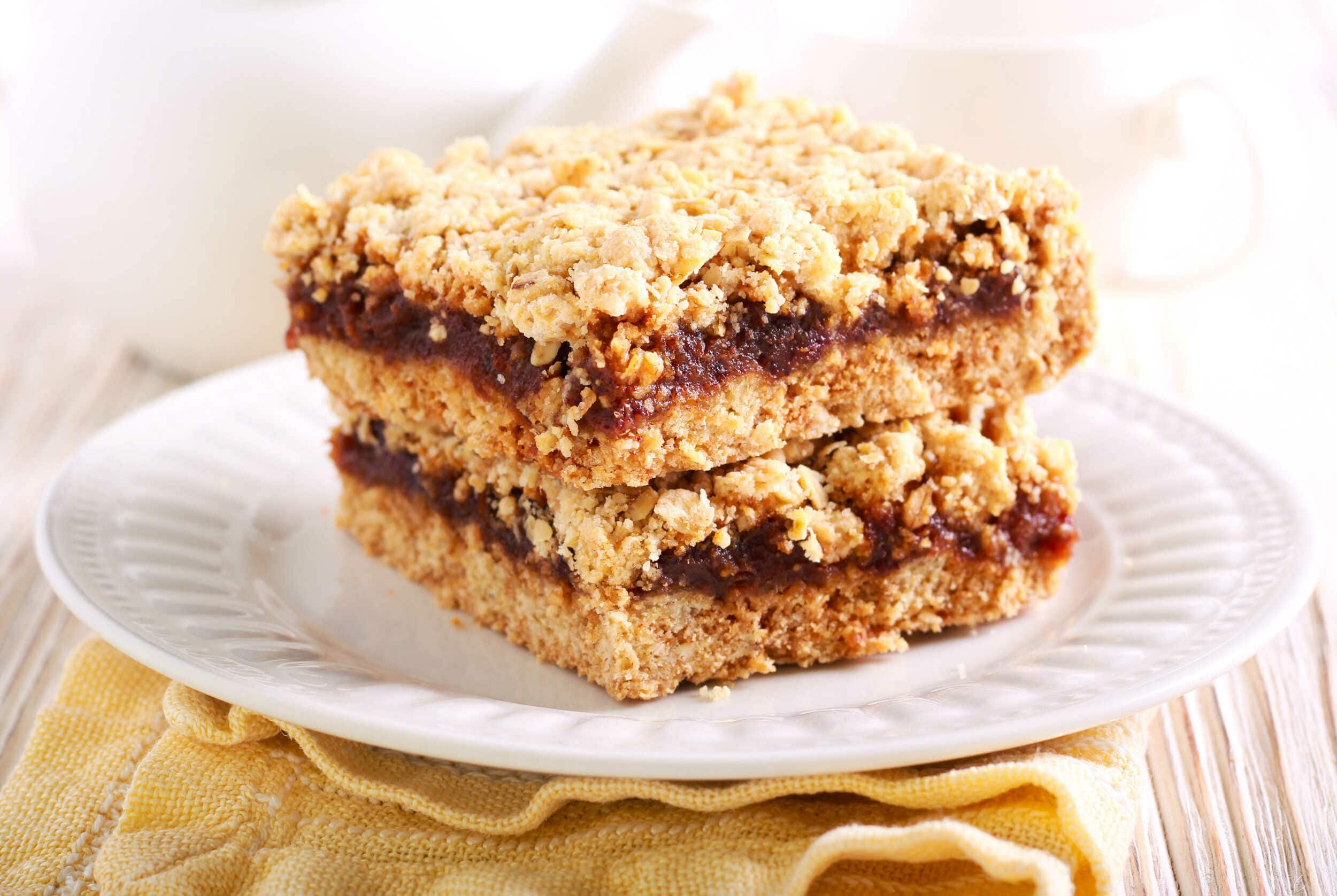 Fruity crumble bars with a crunchy oat topping and a sweet, jammy fruit filling on a white decorative plate. Perfect for dessert or snack, highlighting homemade baked goods and fruit dessert recipes.