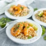 Fresh shrimp taco rice bowls on white plates with lime wedges and cilantro, served with flavorful rice, garnished with herbs, perfect for Mexican-inspired dinner or lunch, vibrant food presentation.