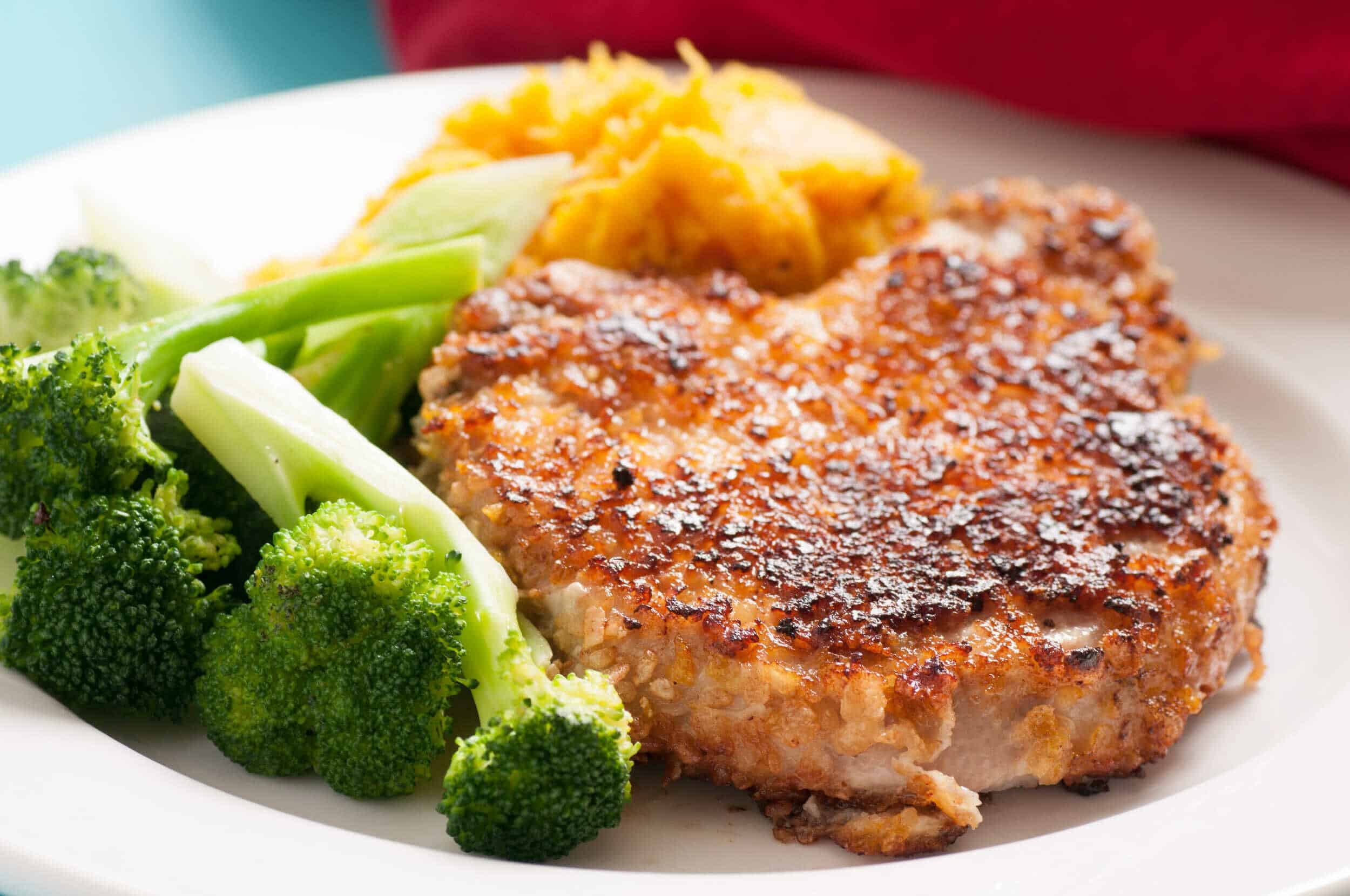 Juicy grilled chicken patty with vegetables and mashed potatoes on a white plate, served with broccoli, celery, and sweet potato mash for a balanced and flavorful meal.