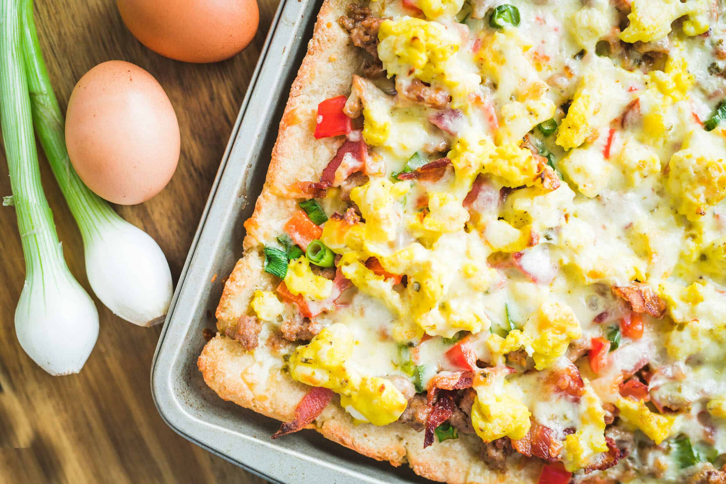 Savory breakfast casserole with scrambled eggs, bacon, cheese, and fresh vegetables in a baking dish. Perfect for brunch or family gatherings, easy to prepare in advance.