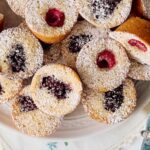 Sweet berry-filled cupcakes dusted with powdered sugar on a decorative plate, perfect for dessert or teatime.