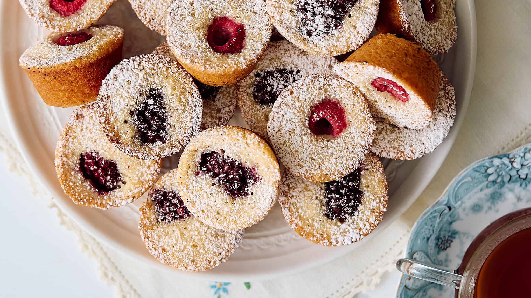 Sweet berry-filled cupcakes dusted with powdered sugar on a decorative plate, perfect for dessert or teatime.