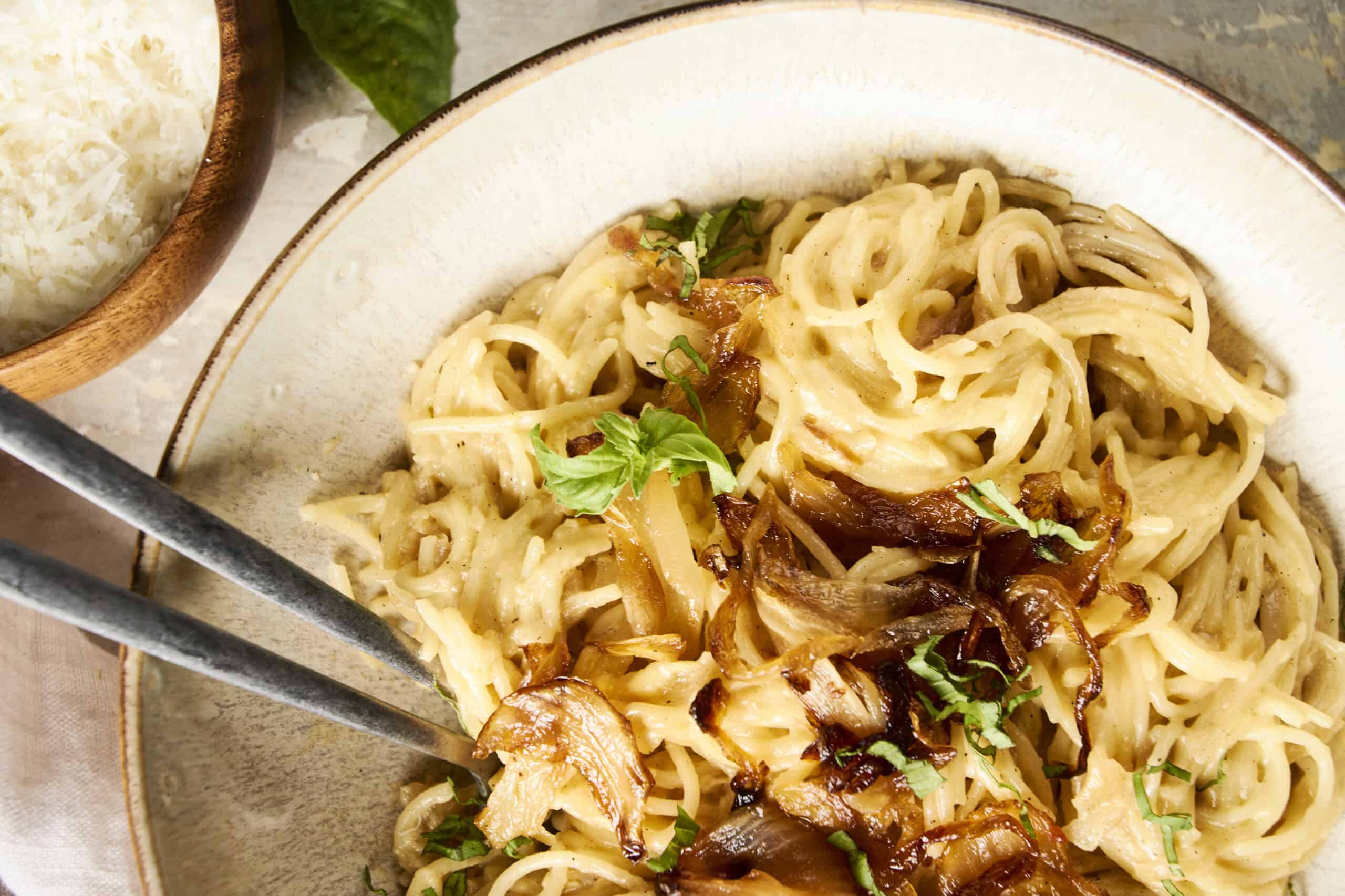 Creamy mushroom Alfredo pasta served on a rustic ceramic plate with chopped herbs and caramelized onions, paired with a bowl of fluffy white rice for a delicious Italian-inspired meal.