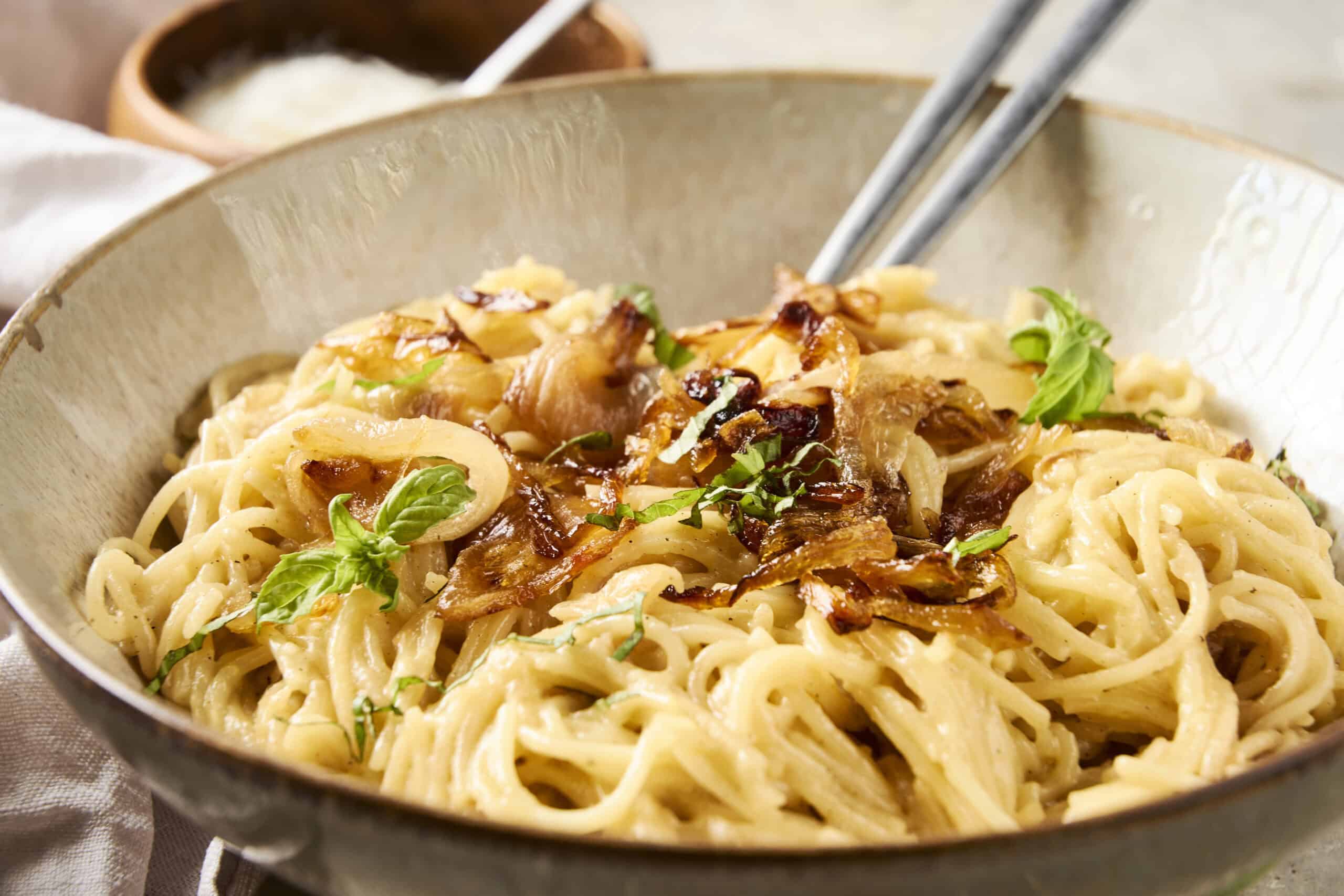 Creamy chicken alfredo pasta dish garnished with fresh basil, served in a rustic bowl with crispy bacon bits and garlic slices for a flavorful Italian-inspired meal.