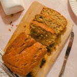 Sweet banana bread loaf sliced on a wooden cutting board with a butter knife. Freshly baked, golden-brown crust, soft interior with banana chunks. Perfect for breakfast or snack.