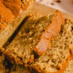 Moist banana bread loaf with a golden-brown crust sliced to reveal a tender crumb. Perfect for breakfast, snacks, or dessert. Easy homemade banana bread recipe for family gatherings or cozy afternoons.