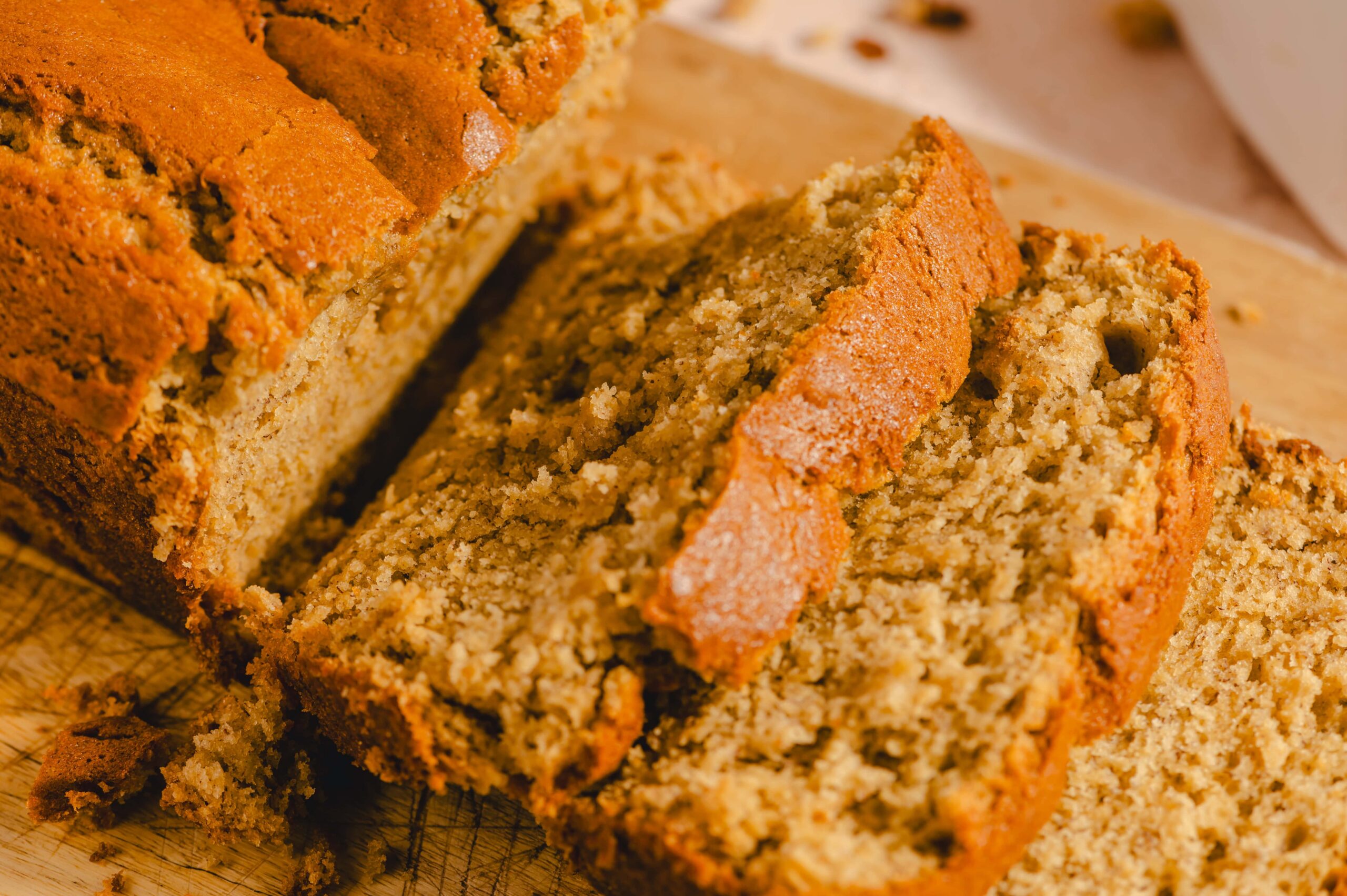 Moist banana bread loaf with a golden-brown crust sliced to reveal a tender crumb. Perfect for breakfast, snacks, or dessert. Easy homemade banana bread recipe for family gatherings or cozy afternoons.