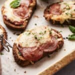 Savory mini pepperoni and cheese pizza bread slices topped with melted cheese and fresh herbs, served on a rustic wooden board. Perfect for snack or appetizer recipes, featuring easy-to-make pizza bread ideas.