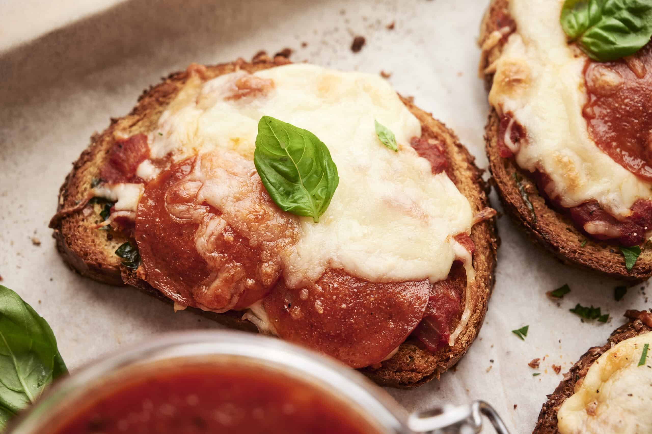 Savory baked bread topped with tomato sauce, melted cheese, and fresh basil leaves, perfect for homemade pizza or Italian-inspired appetizers.