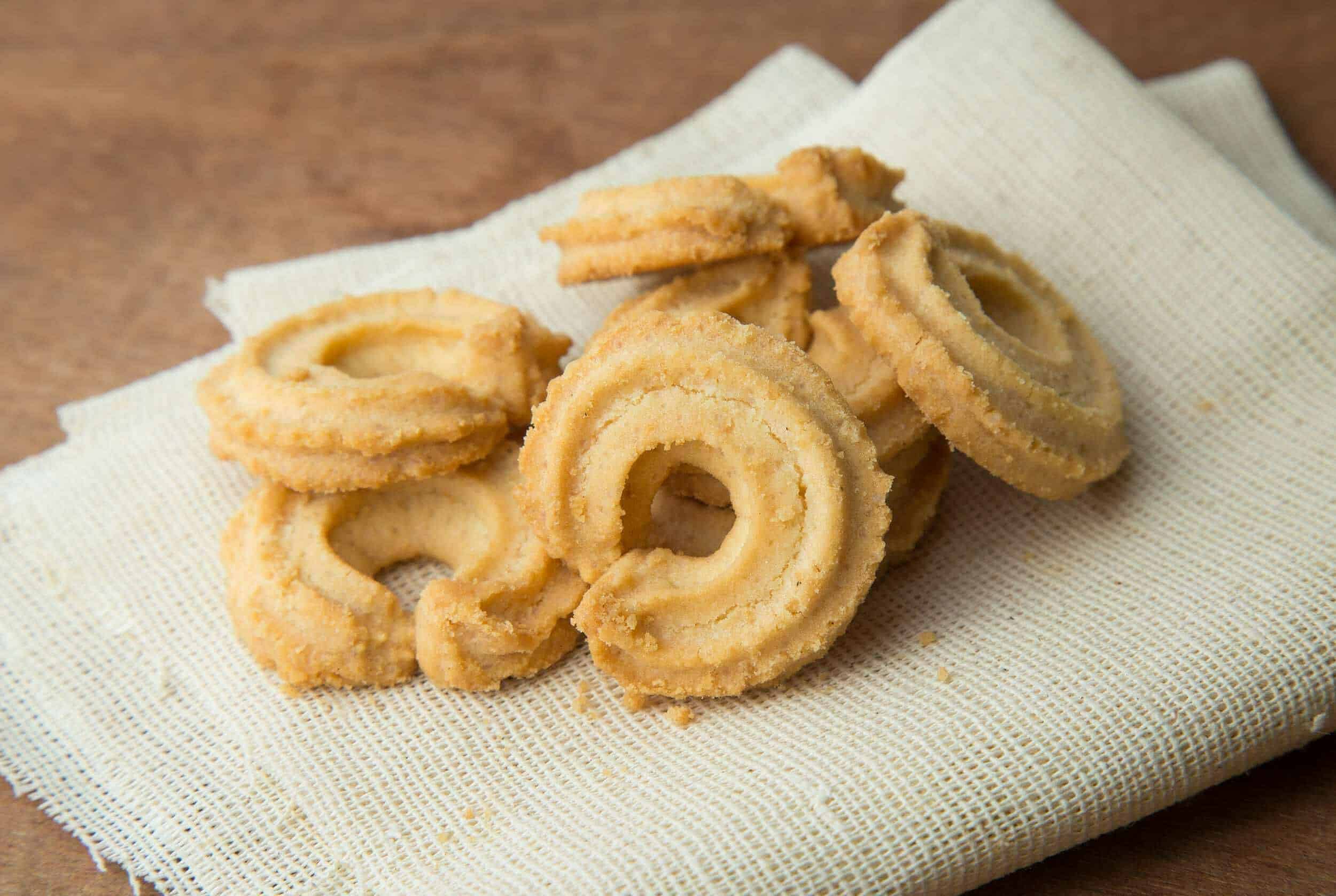 Crispy onion rings on a white cloth napkin with a wooden background, perfect for appetizer recipes and snack ideas.