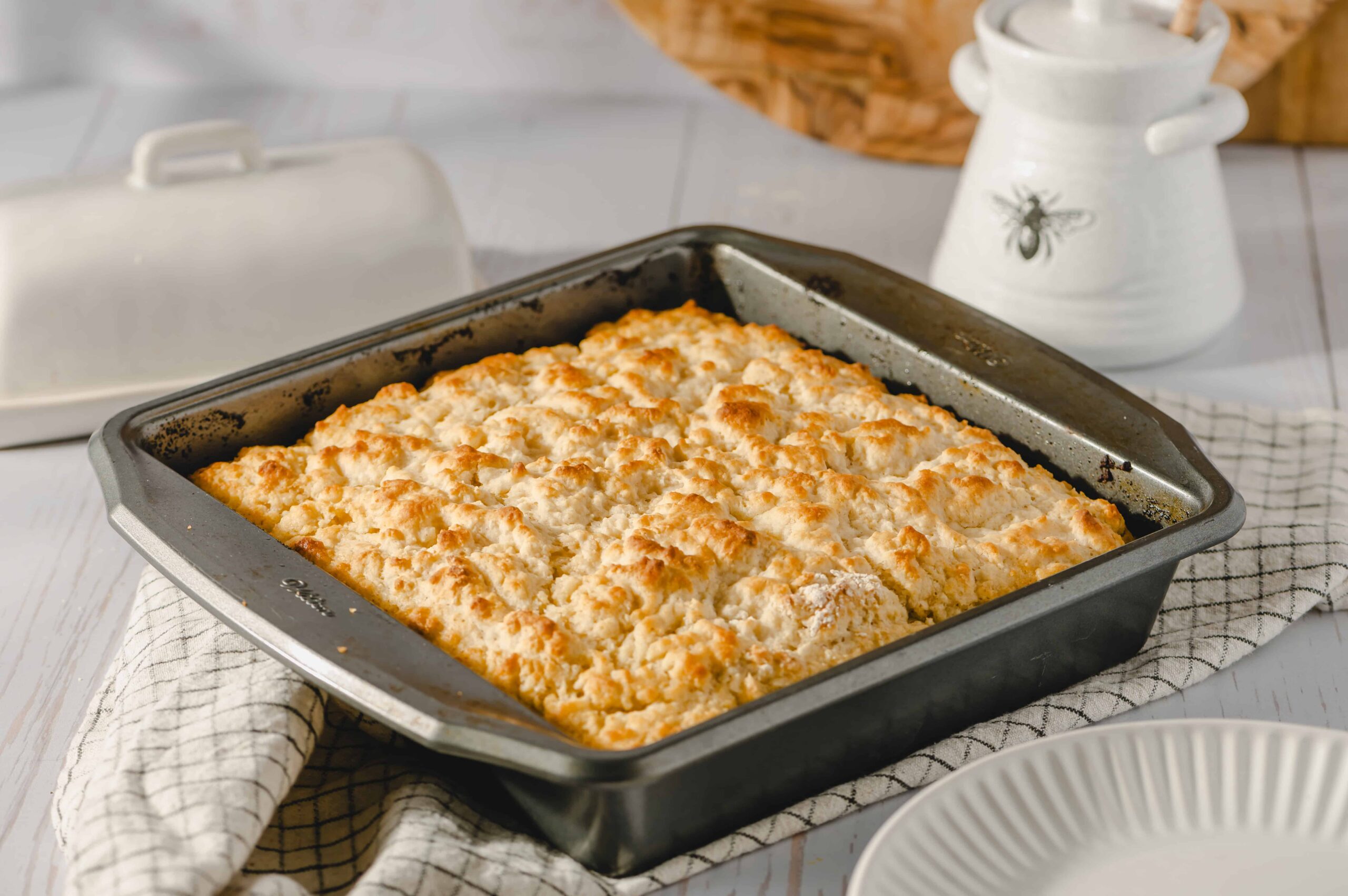 Baked crumb-topped casserole dish on a rustic kitchen table, ready to serve, with a white plate and decorative jar in the background, showcasing comforting homemade comfort food.