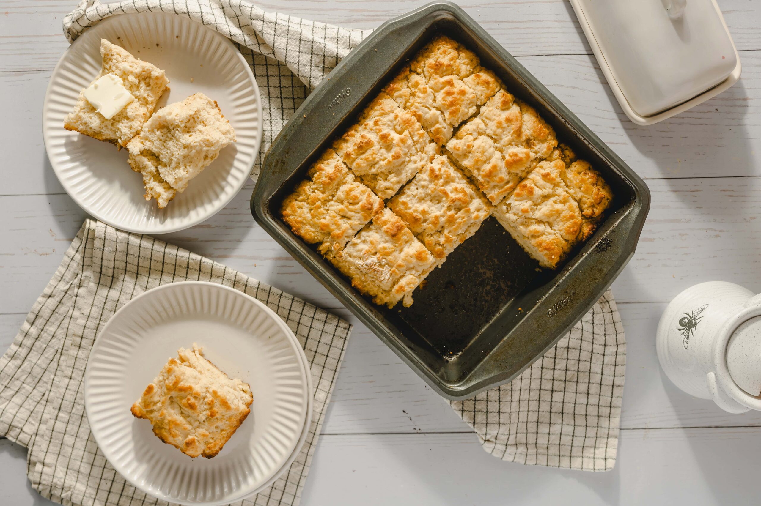 Butterscotch Lemon Bars, baked to golden perfection, served on white plates with a checkered cloth, showcasing their flaky crust and tart lemon filling, perfect for dessert or afternoon tea.
