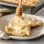 Fluffy homemade shortbread served with honey drizzled on top, on a white plate with a honey dipper. Perfect for baking and dessert recipes, showcasing a delicious, fresh-baked treat.