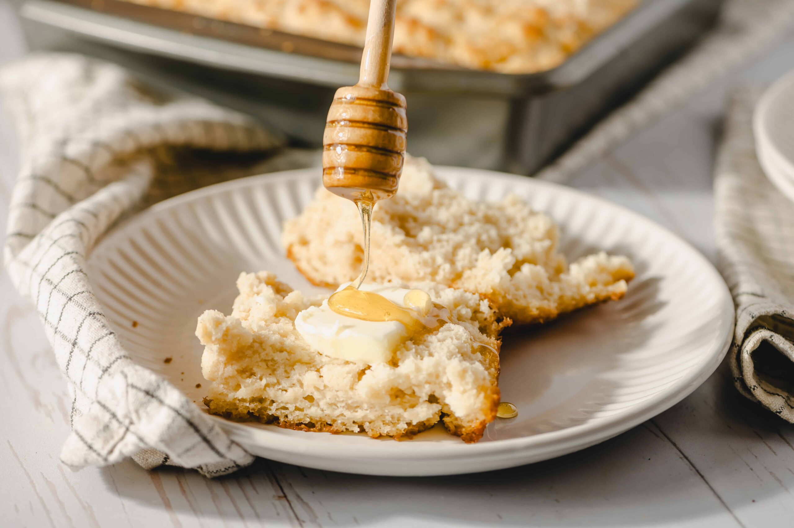 Fluffy homemade shortbread served with honey drizzled on top, on a white plate with a honey dipper. Perfect for baking and dessert recipes, showcasing a delicious, fresh-baked treat.