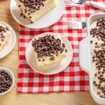 Creamy vanilla dessert with chocolate chips on top, served in slices on a white plate, ideal for dessert recipes and gatherings.