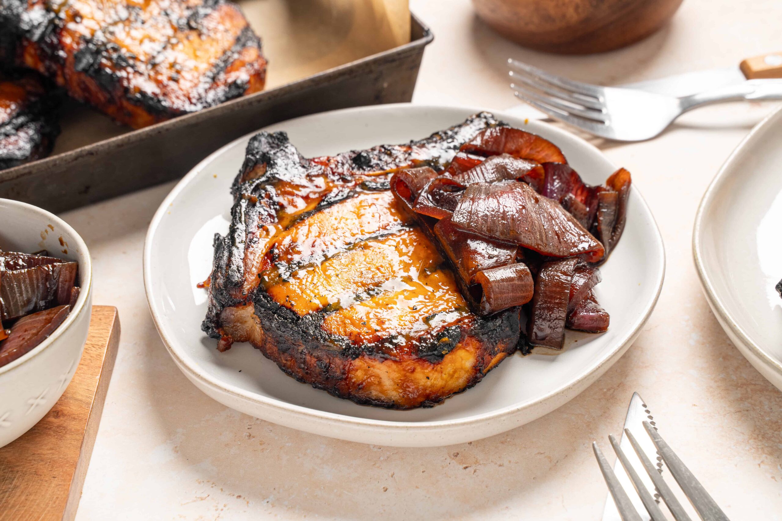 Juicy grilled steak topped with melted cheese served with caramelized onions on a white plate. Perfect for a hearty dinner, complemented by tender, flavorful roasted vegetables and a rustic meal presentation.