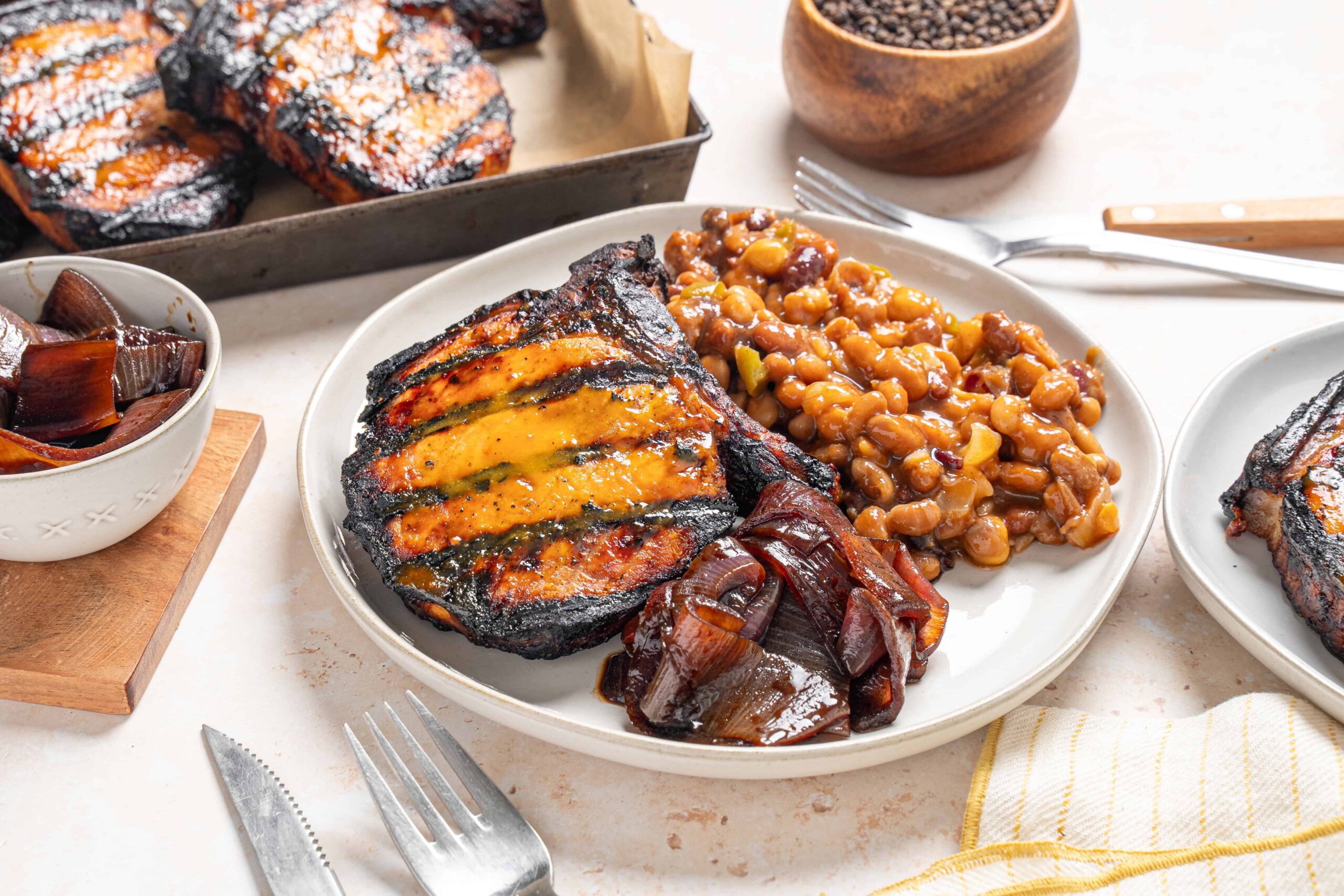 Succulent grilled ribeye steak with colorful vegetable toppings served with baked sweet potatoes and side dishes, showcasing a hearty, flavorful meal.