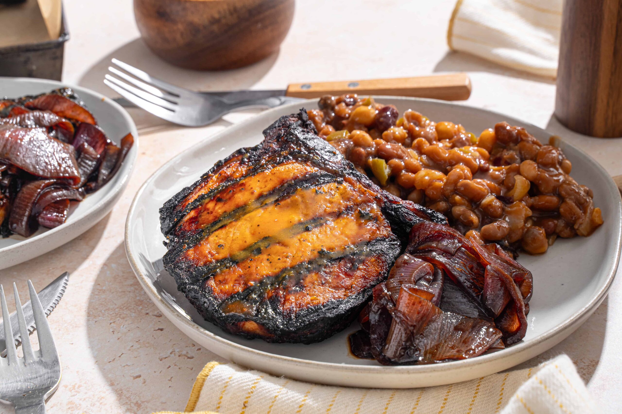 Baked fish fillet with tomato sauce served with baked beans and caramelized onions on a white ceramic plate.