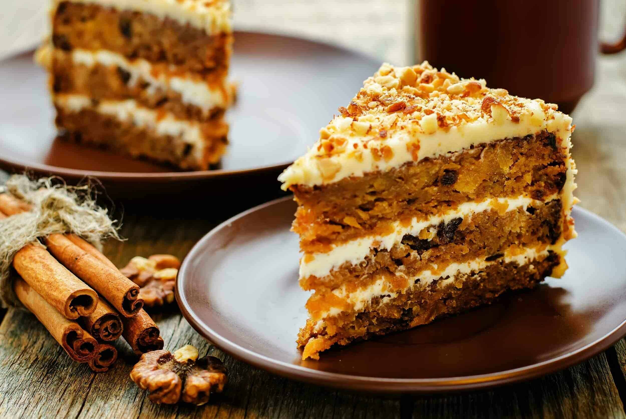 Rich, moist carrot cake with cream cheese frosting and crunchy toasted nuts, served on rustic plates for a delectable dessert experience.