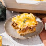 Creamy beef and cheese casserole with golden mashed potatoes and herbs, served on a rustic plate, perfect for comfort food and family dinners.